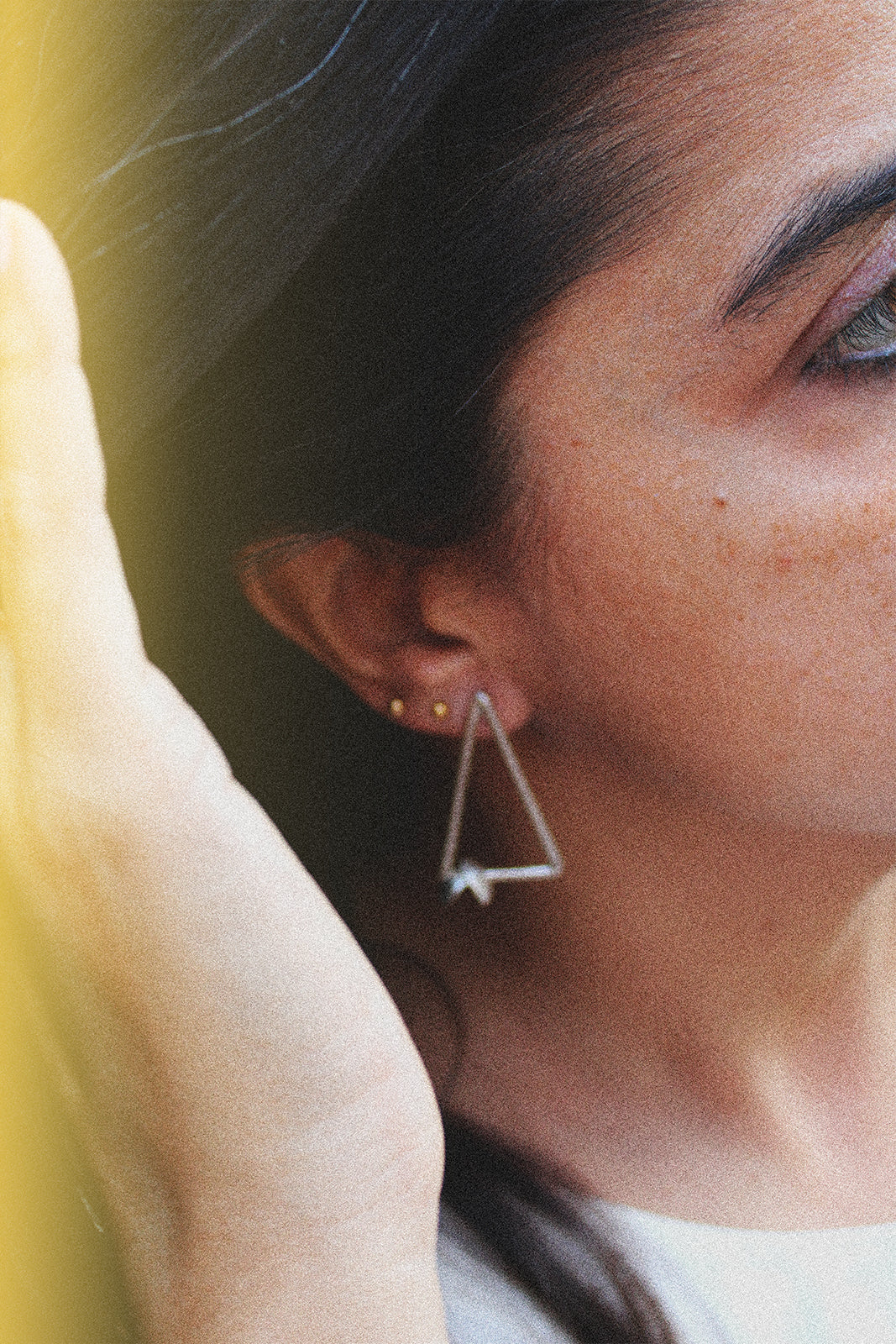 Close-up of a person wearing a geometric silver earring with a blurred background
