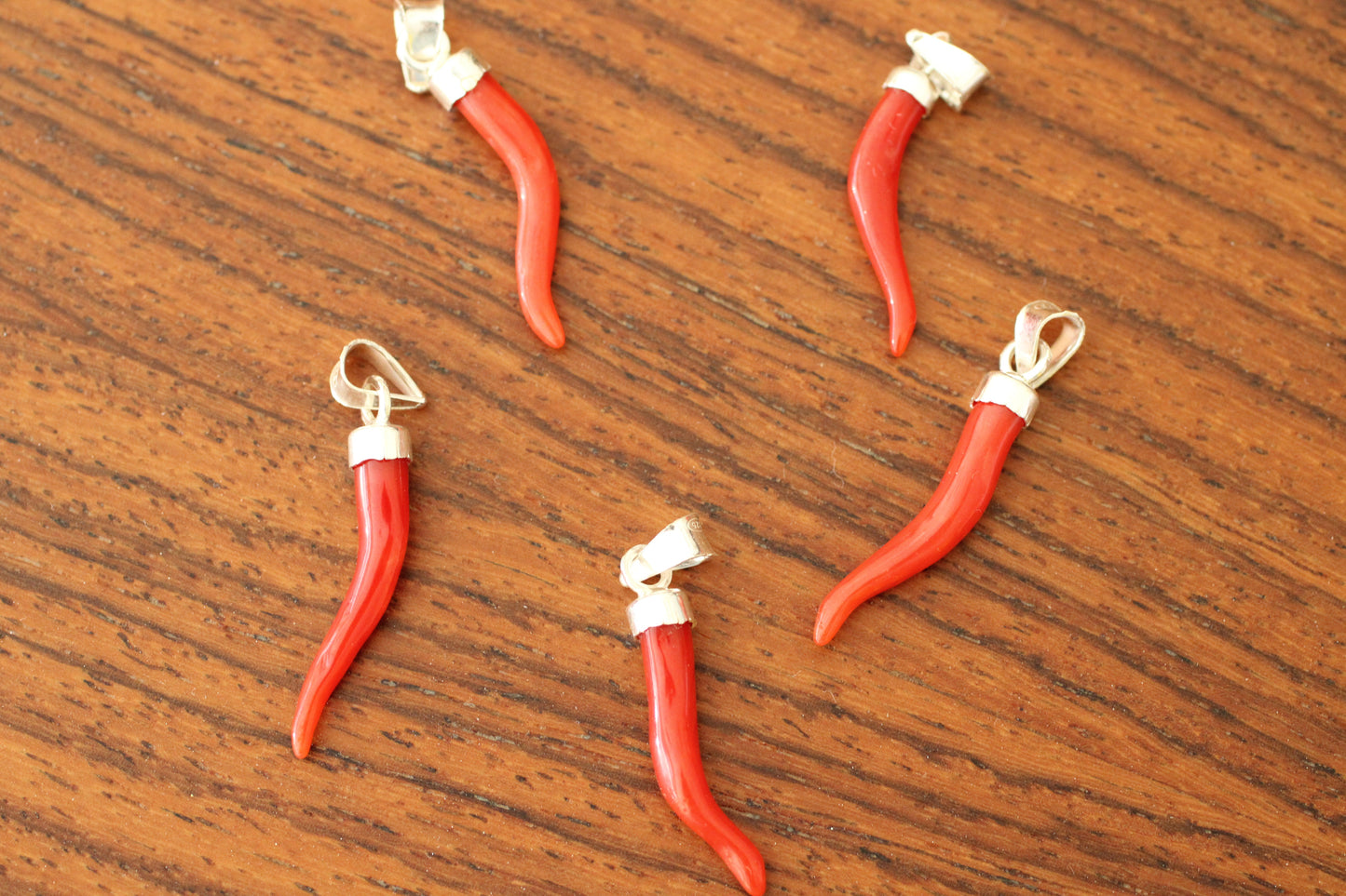 Red coral pendants on a silver chain against a wooden background