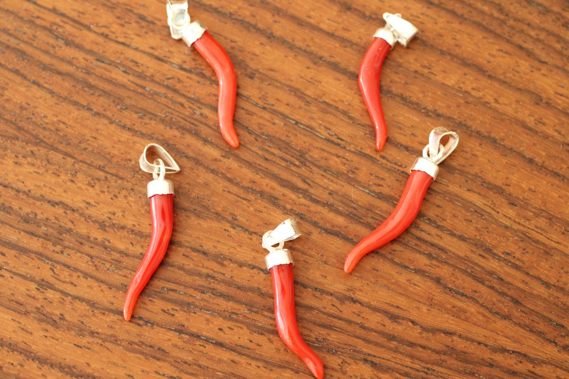 Red coral pendants on a silver chain against a wooden background