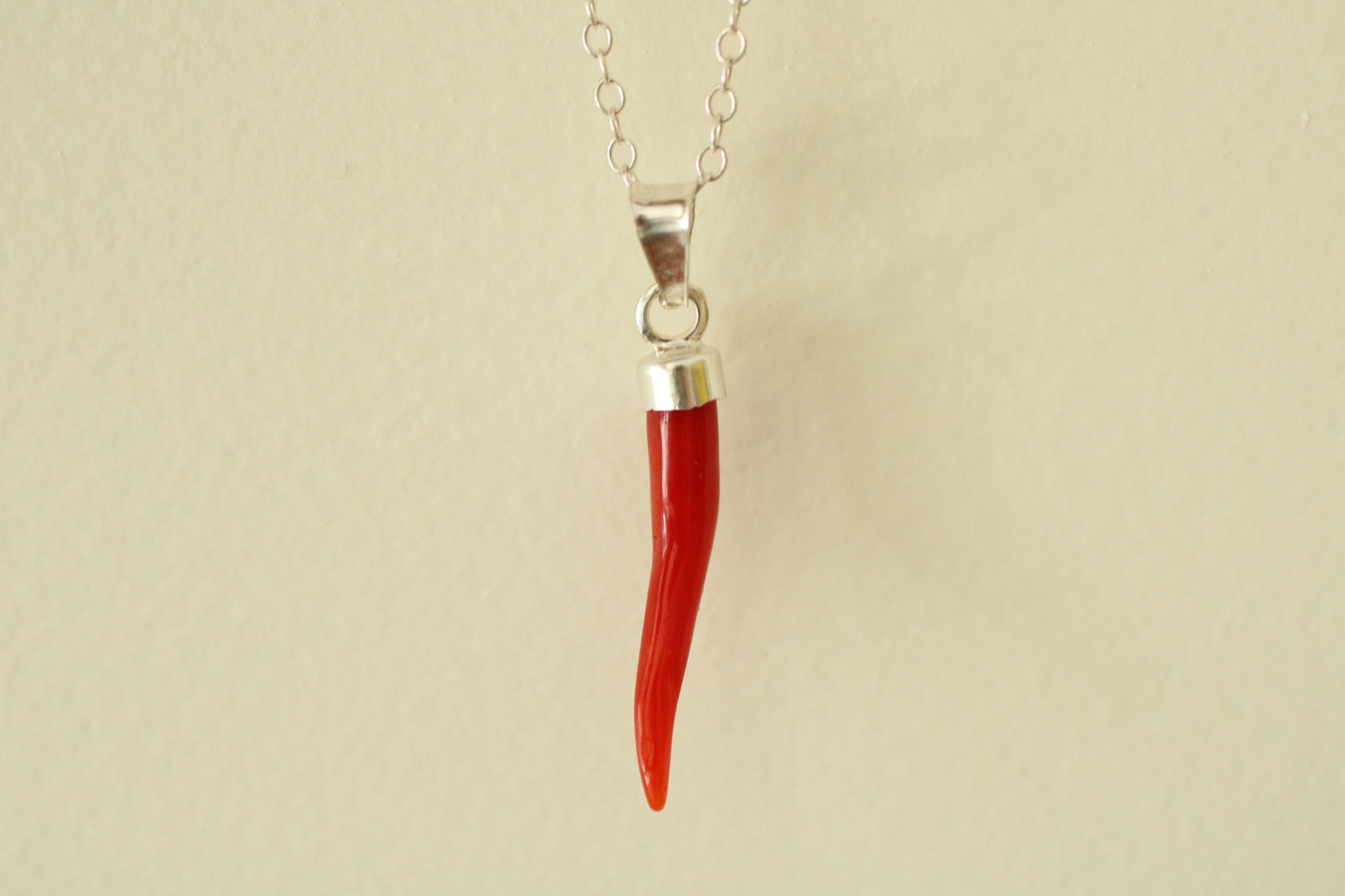 Red coral pendant on a silver chain against a white background