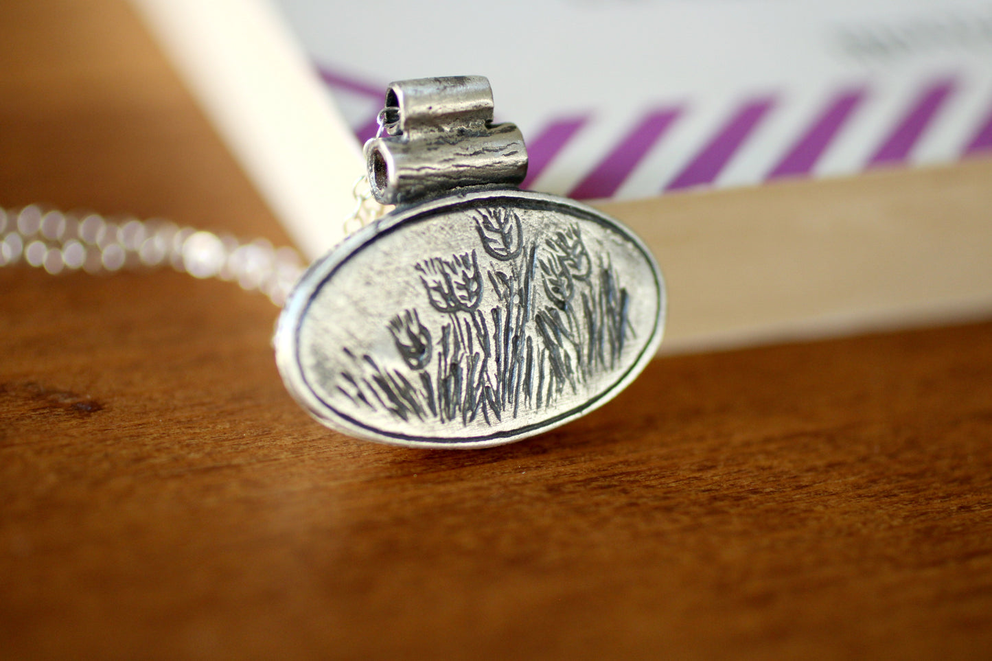 SIlver pendant with an oval shape with grain design engraved
