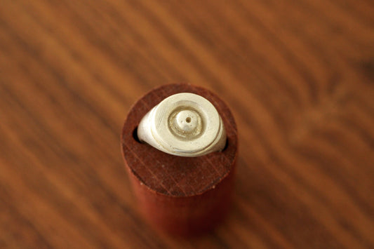 Close-up of a silver ring with a ball shape in the center on a brown surface
