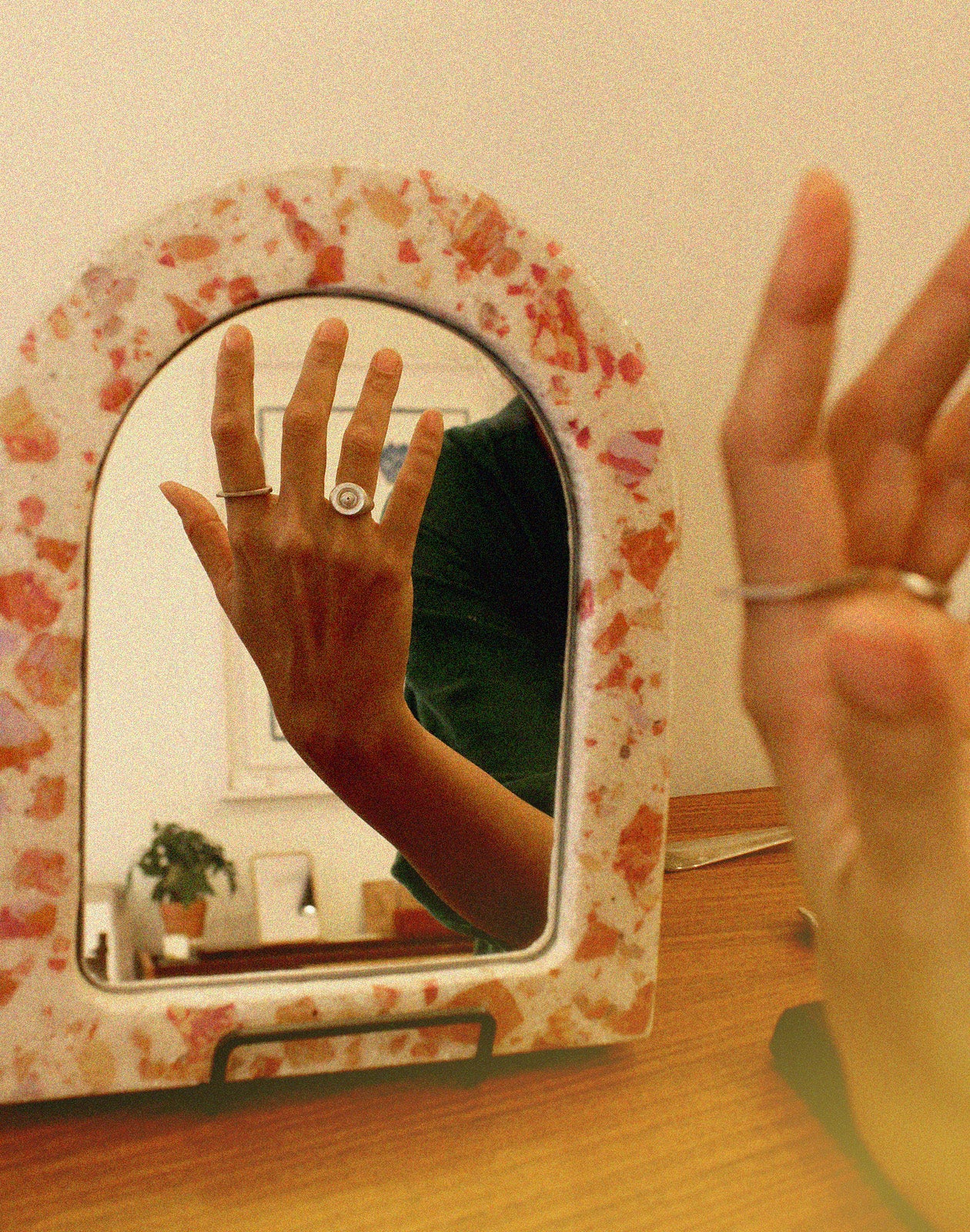 Person reflecting their hand in a concrete mirror with a silver ring