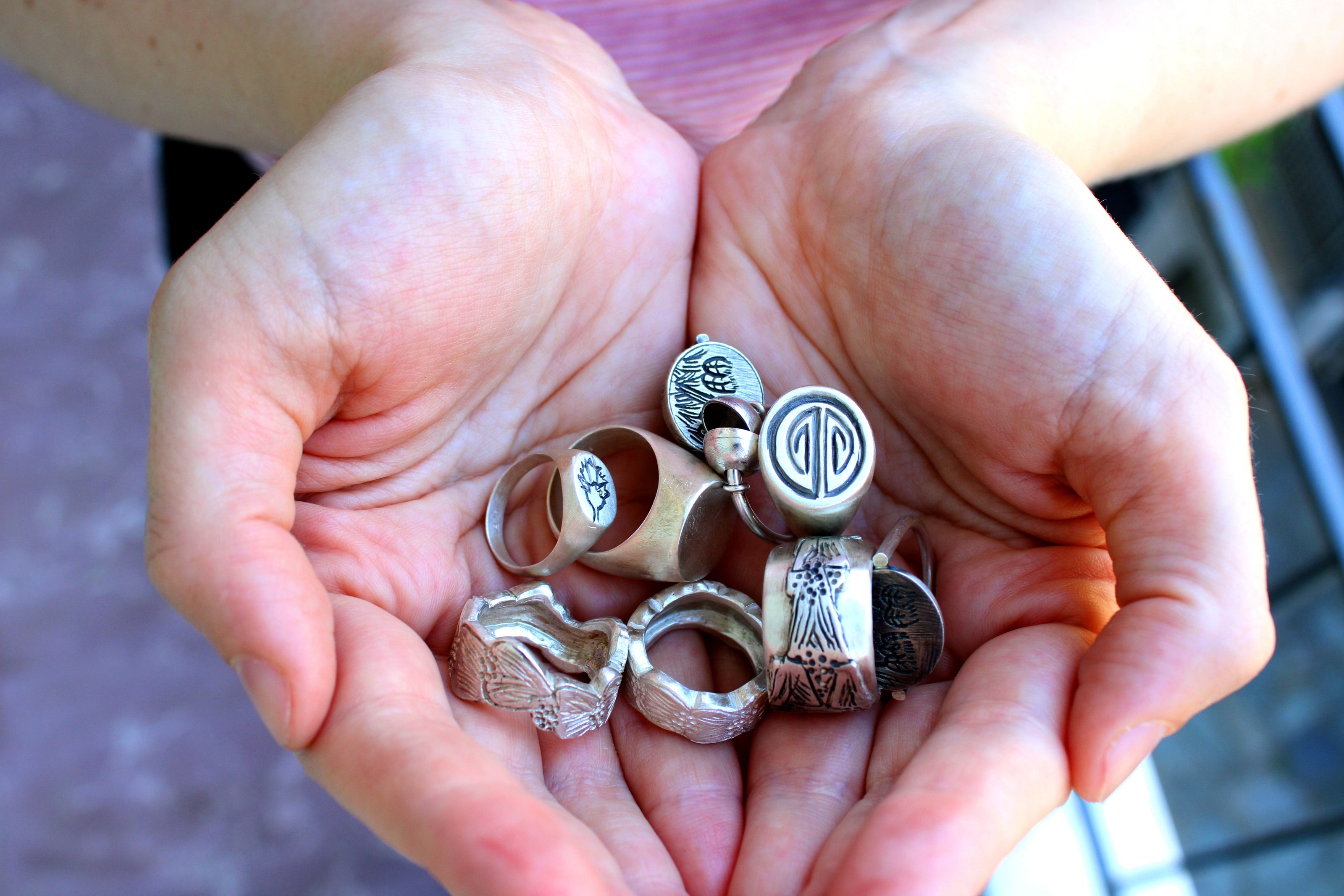 Close-up of hands together holding a few pieces of silver jewelry