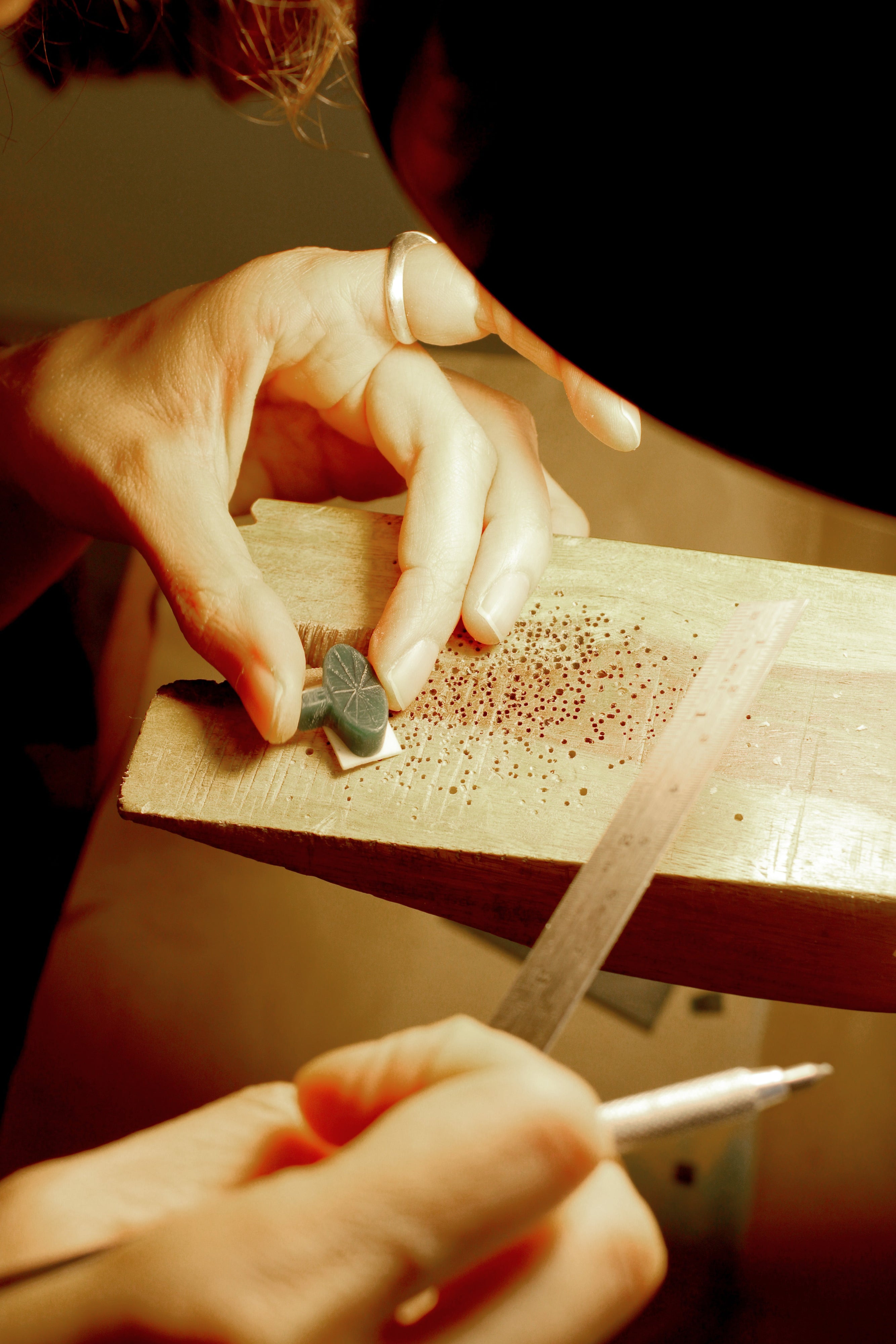 Person working on a small wax block with a carving tool