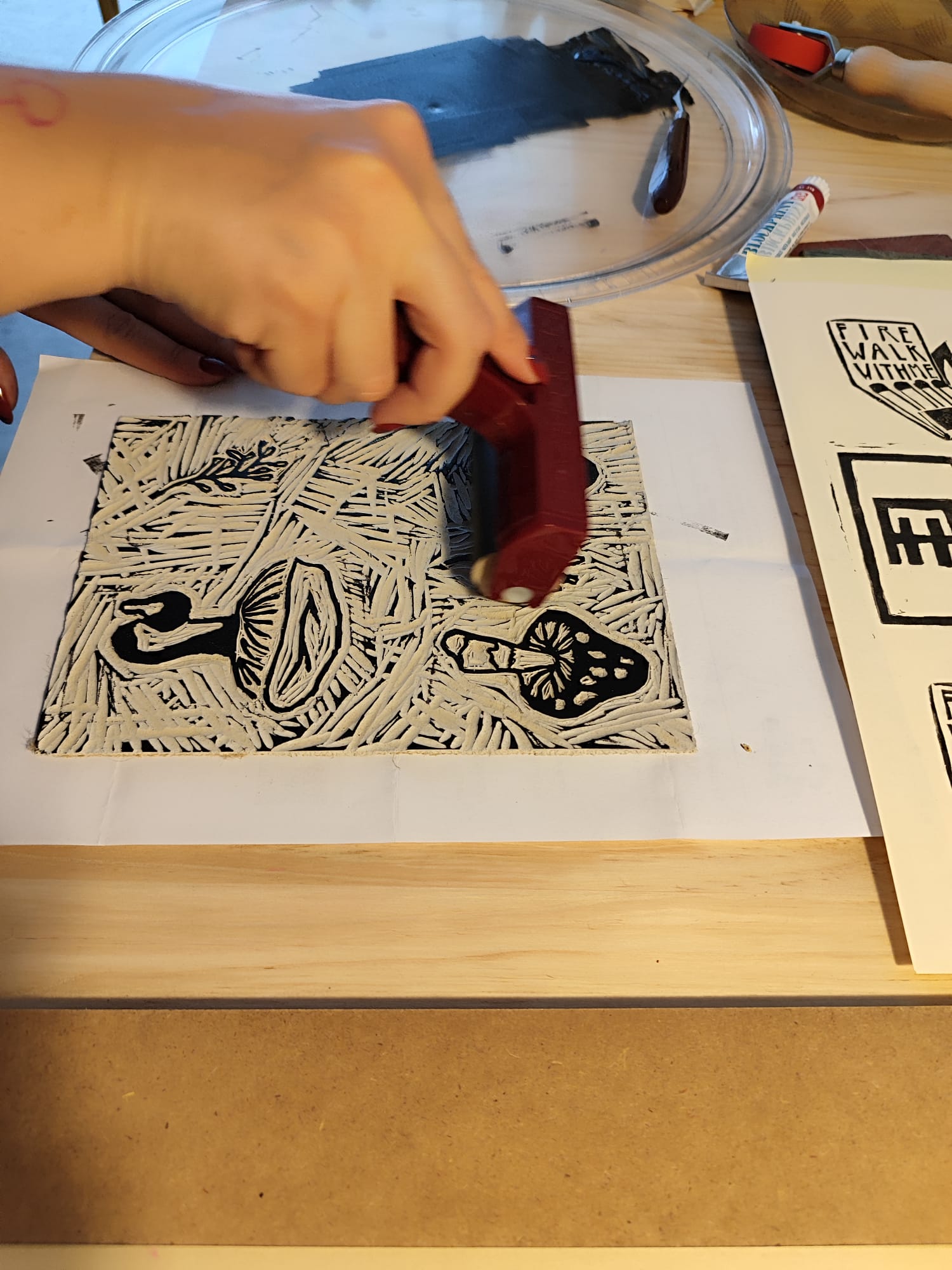 Hand printing a black and white design onto paper with a linocut block.
